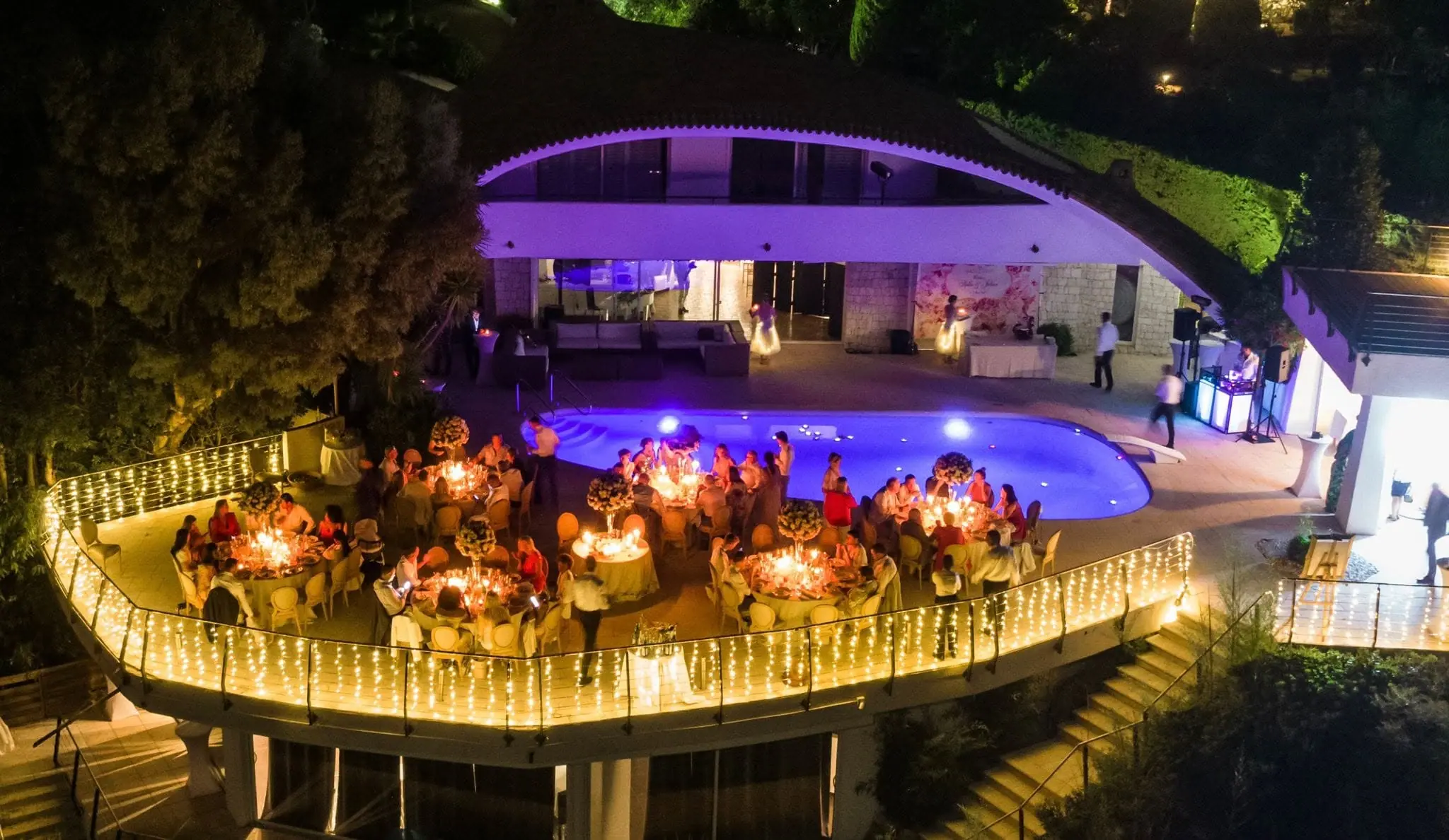 Aerial view of an evening celebration around the illuminated pool